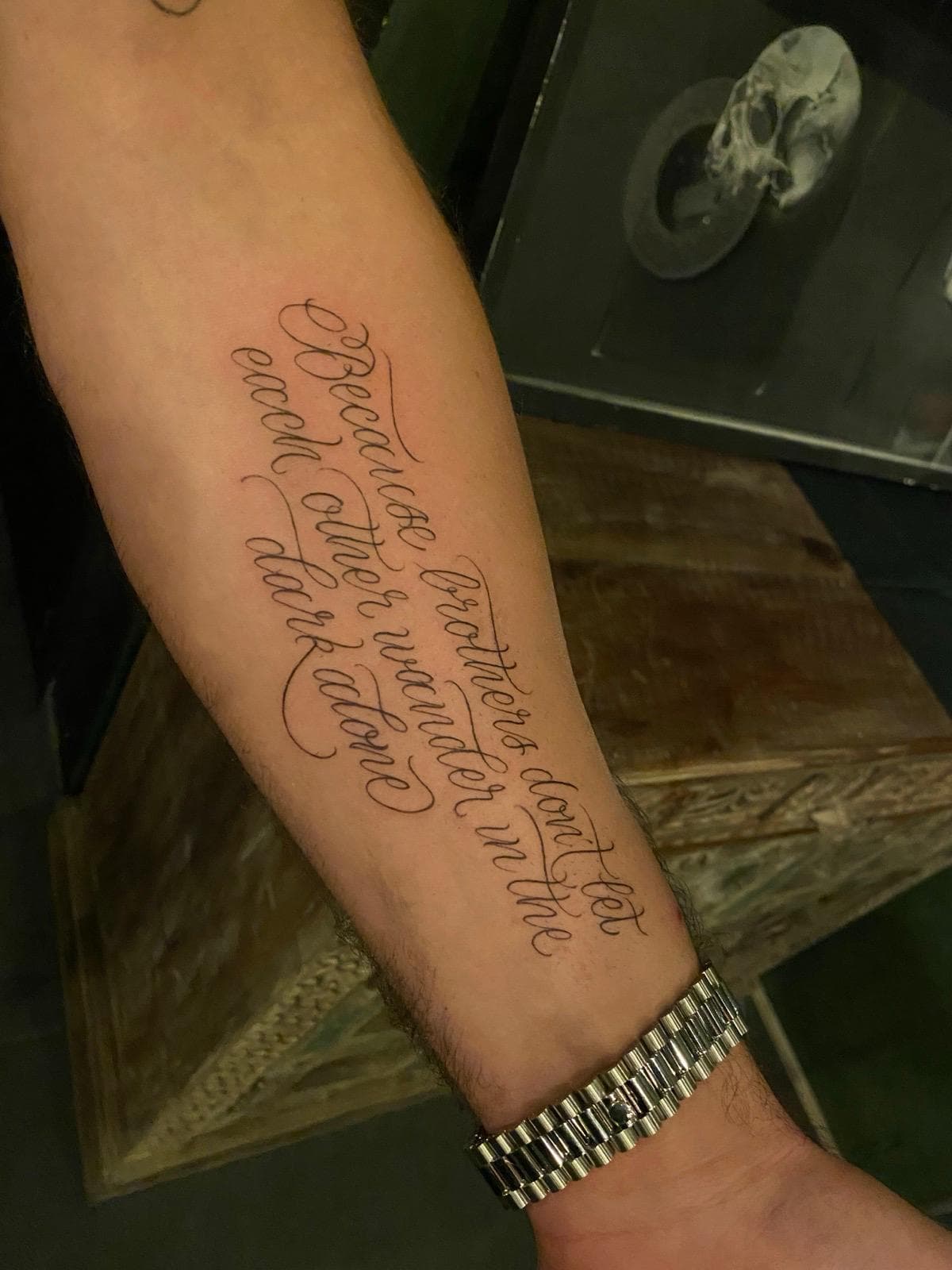 Kalligrafie lettering tattoo op onderarm — because brothers don't let each other wander alone