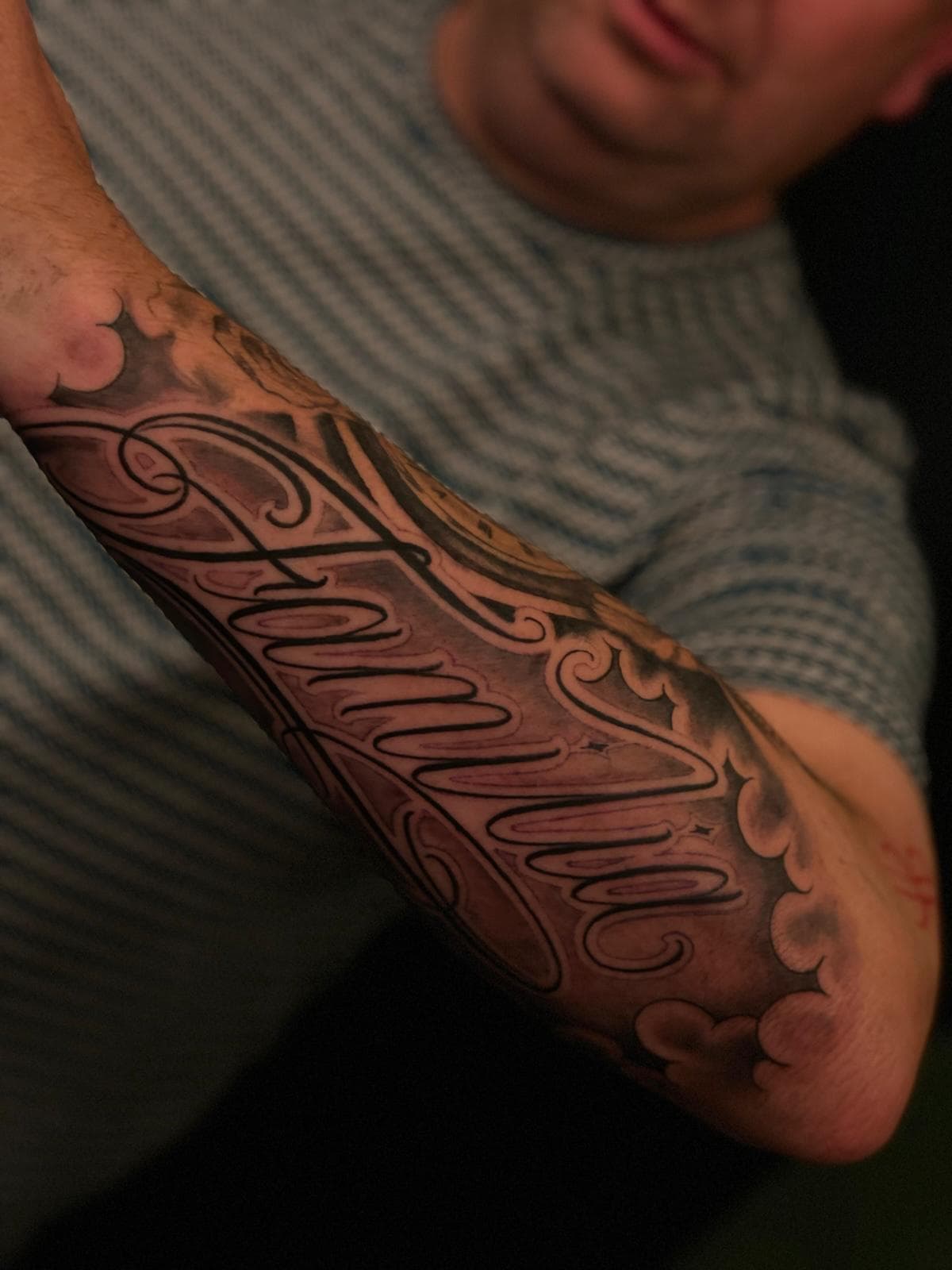 Chicano script lettering tattoo op onderarm — Familia